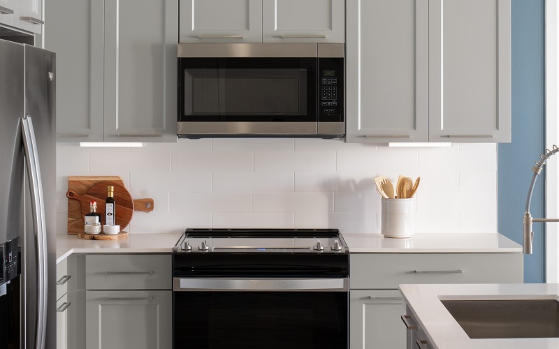 Luxury Apartments in Orlando, FL with In-Unit Washer and Dryer - Aventon Isabelle - Kitchen with Gray Cabinets, White Counters, White Tile Backsplash, and Stainless Steel Appliances